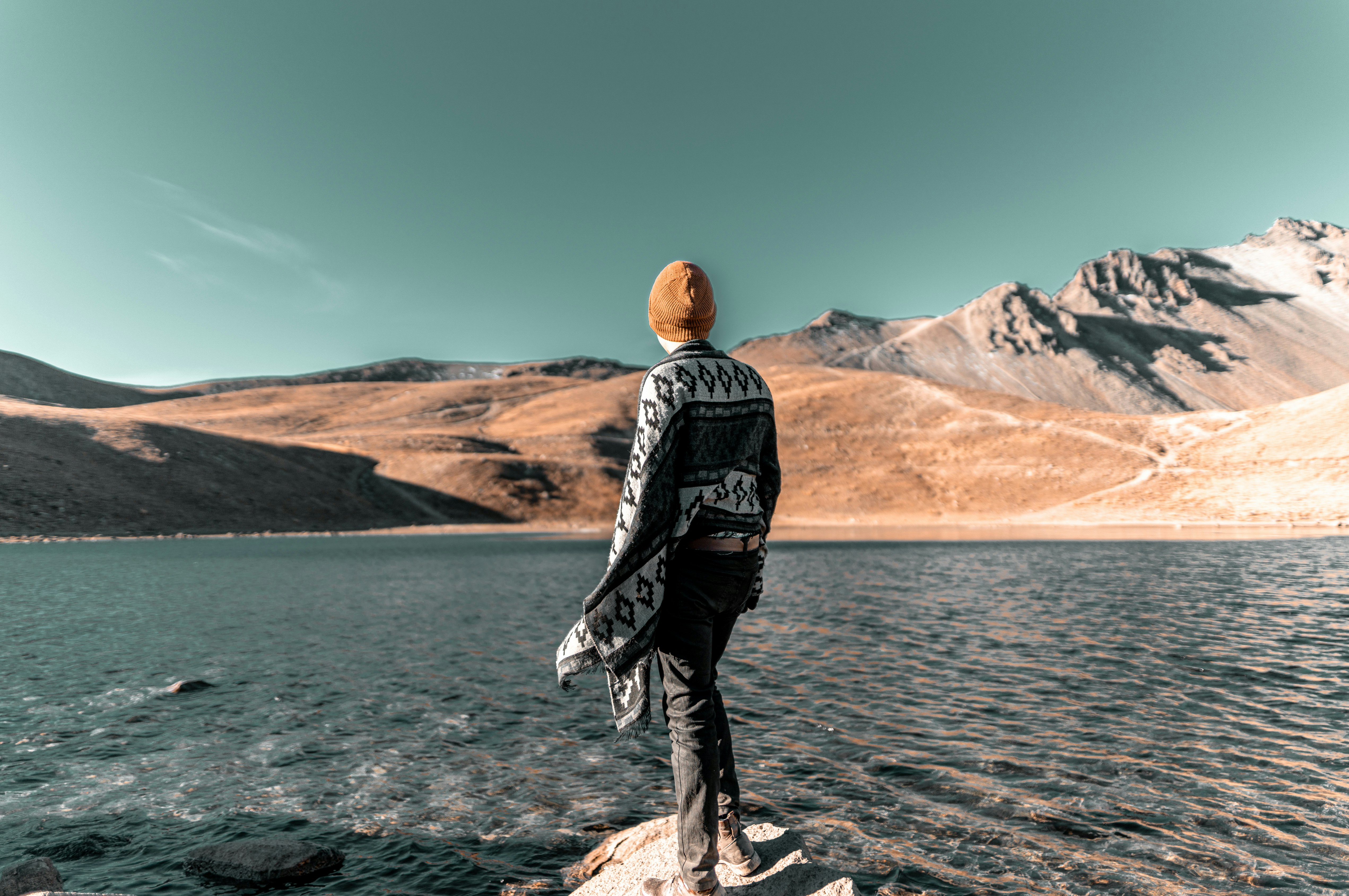 person standing on rock near body of water